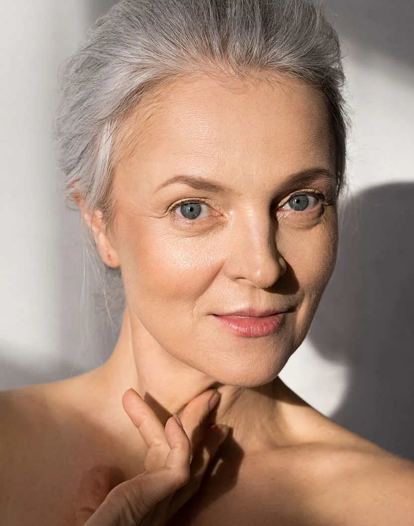 Close up shot of a woman with silver hair and blue eyes gently touches her neck, smiling softly in natural light. - Marionette Lines in New York, NY